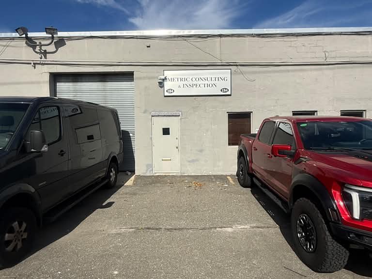 Front of the Metric Consulting & Inspection building with vehicles parked outside