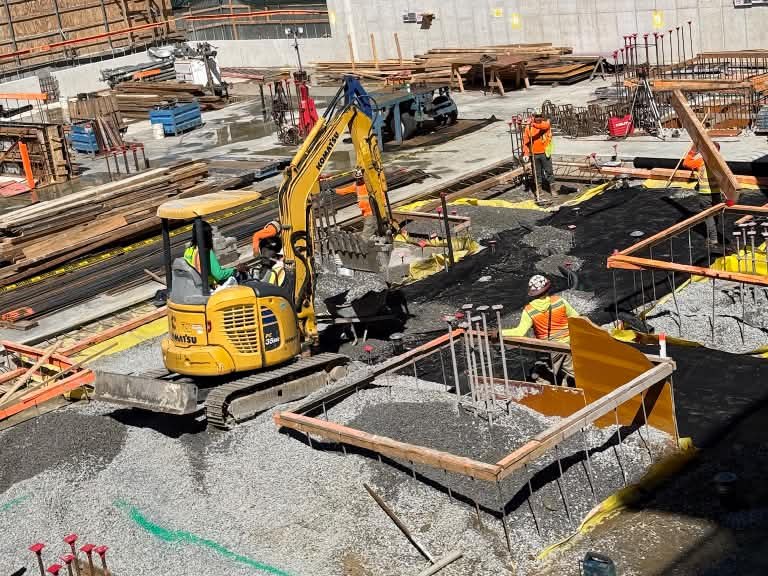 Excavator spreading gravel for footings on a New York City site