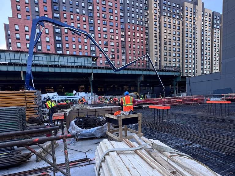 Concrete pump boom over a job site with apartment buildings behind