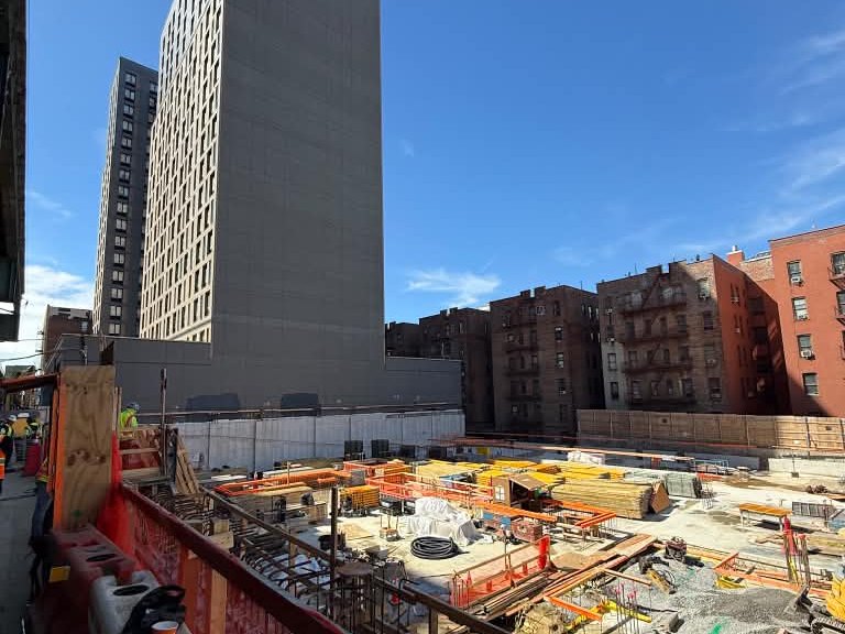 Construction site in New York City with a high-rise tower behind